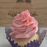 Bubble gum buttercream cupcake with pink swirled frosting in a purple liner