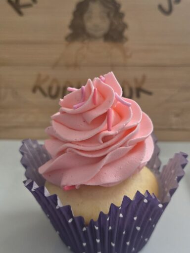 Bubble gum buttercream cupcake with pink swirled frosting in a purple liner