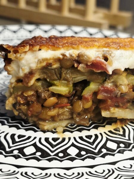 Slice of vegetarian lentil moussaka served on a plate showing layered vegetables and béchamel