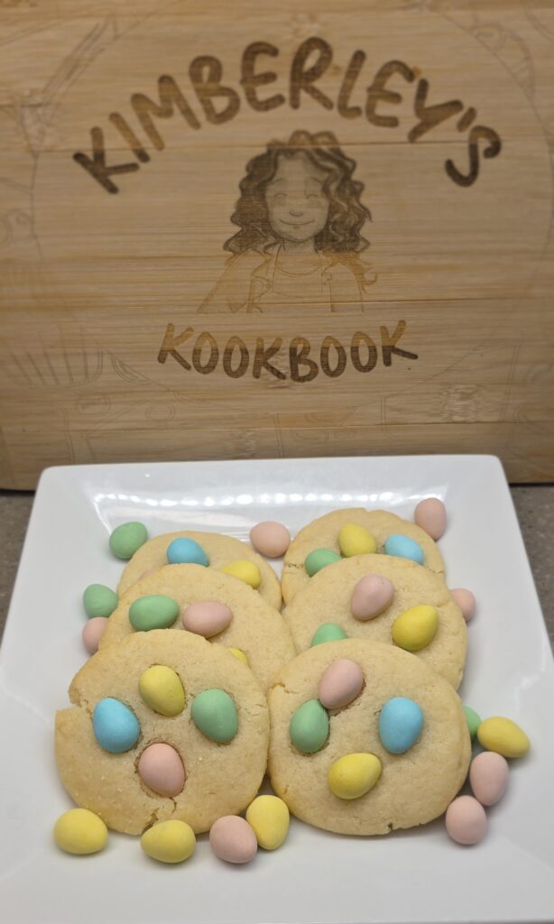 Mini eggs sugar cookies arranged on a serving board with a cozy kitchen background, perfect for Easter baking