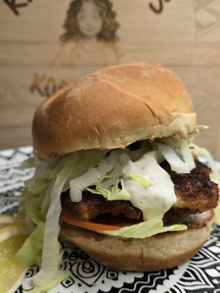 Crispy fish sandwich with garlic herb tartar sauce on a toasted bun with lettuce and tomato