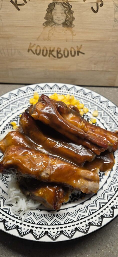 Sweet and sour spare ribs served over rice with corn, coated in a glossy homemade sauce