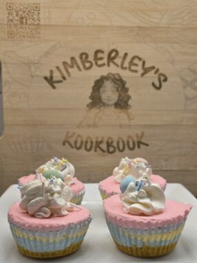 Mini no-bake Easter cheesecakes with pastel layers and whipped cream topping on a wooden board