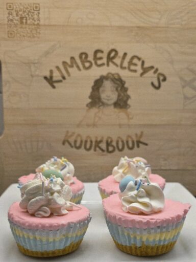 Mini no-bake Easter cheesecakes with pastel layers and whipped cream topping on a wooden board