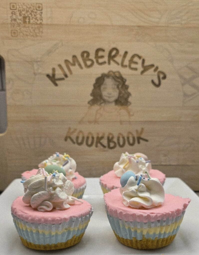 Mini no-bake Easter cheesecakes with pastel layers and whipped cream topping on a wooden board